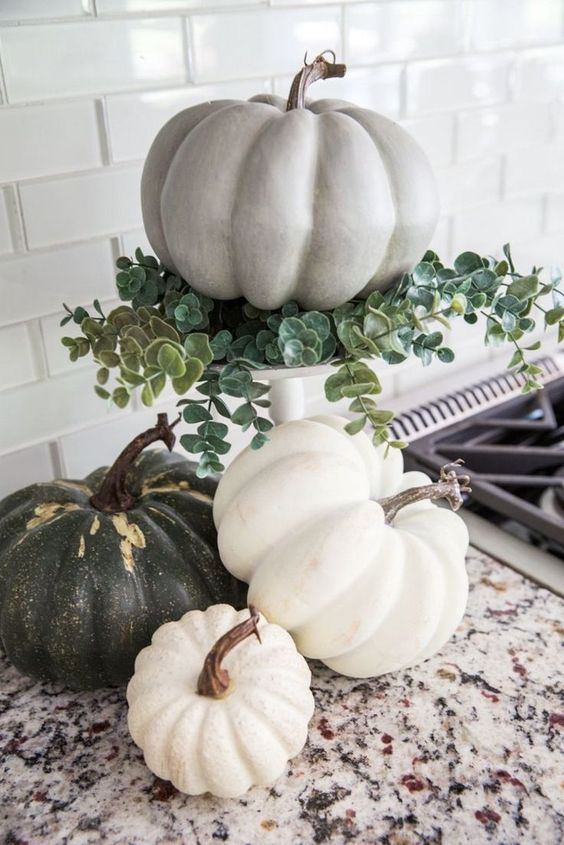 Green and white pumpkins stacked on granite kitchen countertop