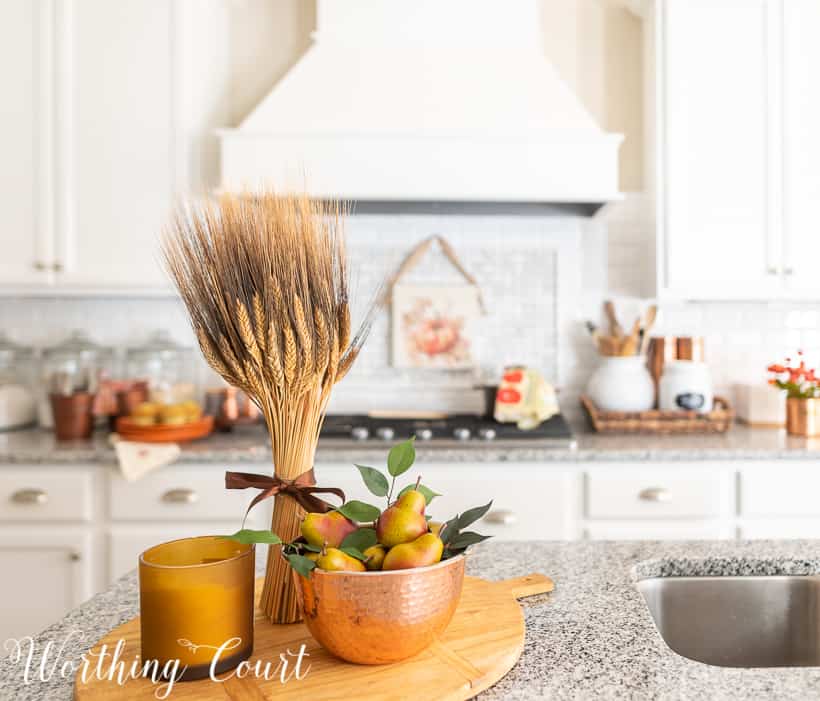 Fall wheat with bowl of pears on wooden cutting board